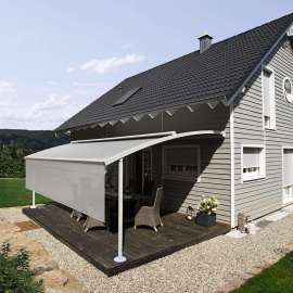 graues Holzwohnhaus mit weißer Markise über der Terrasse